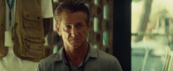 Movie still from “The Gunman” (2015), directed by Pierre Morel – A person wearing a gray shirt; Close Up shot, Over the shoulder angle