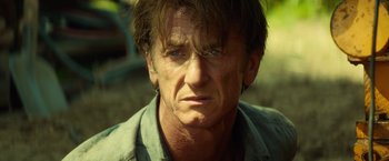 Movie still from “The Gunman” (2015), directed by Pierre Morel – A person wearing a green shirt; Close Up shot, Over the shoulder angle
