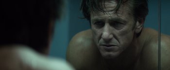 Movie still from “The Gunman” (2015), directed by Pierre Morel – A man's face in a dark room; Close Up shot, Over the shoulder angle