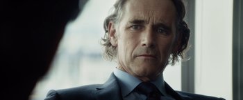 Movie still from “The Gunman” (2015), directed by Pierre Morel – A person wearing a suit and tie; Close Up shot, Over the shoulder angle