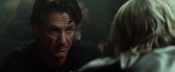 Movie still from “The Gunman” (2015), directed by Pierre Morel – A person sitting in front of another person; Close Up shot, Over the shoulder angle
