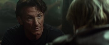 Movie still from “The Gunman” (2015), directed by Pierre Morel – A person sitting in front of another person; Close Up shot, Over the shoulder angle