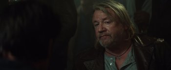 Movie still from “The Gunman” (2015), directed by Pierre Morel – A person with long hair and a beard; Close Up shot, Over the shoulder angle