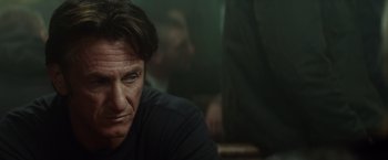 Movie still from “The Gunman” (2015), directed by Pierre Morel – A person sitting in front of a window; Close Up shot, Low angle