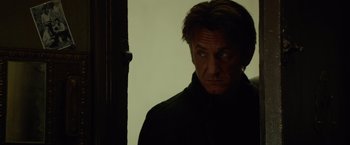 Movie still from “The Gunman” (2015), directed by Pierre Morel – A person wearing a black jacket; Close Up shot, Over the shoulder angle