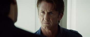 Movie still from “The Gunman” (2015), directed by Pierre Morel – A person looking at the camera; Close Up shot, Over the shoulder angle