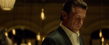 Movie still from “The Gunman” (2015), directed by Pierre Morel – A person wearing a suit and tie; Close Up shot, Low angle