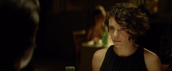 Movie still from “The Gunman” (2015), directed by Pierre Morel – A woman sitting in front of a wine glass; Close Up shot, Over the shoulder angle