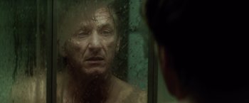 Movie still from “The Gunman” (2015), directed by Pierre Morel – A man looking into a bathroom mirror; Close Up shot, Over the shoulder angle