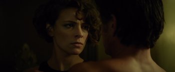 Movie still from “The Gunman” (2015), directed by Pierre Morel – A person's face in a dark room; Close Up shot, Over the shoulder angle