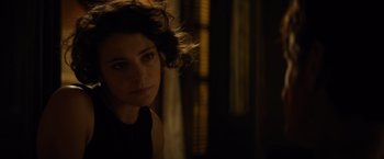 Movie still from “The Gunman” (2015), directed by Pierre Morel – A woman with curly brown hair in a dark room; Close Up shot, Over the shoulder angle