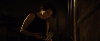 Movie still from “The Gunman” (2015), directed by Pierre Morel – A woman in a black dress writing in a notebook; Close Up shot, High angle