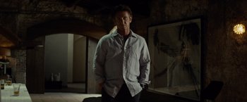 Movie still from “The Gunman” (2015), directed by Pierre Morel – A man standing in a room with his hands in his pockets; Medium shot, Low angle