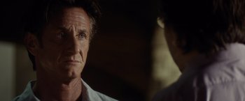 Movie still from “The Gunman” (2015), directed by Pierre Morel – A person wearing a white shirt; Close Up shot, Over the shoulder angle