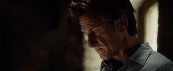 Movie still from “The Gunman” (2015), directed by Pierre Morel – A person looking at the camera; Close Up shot, Low angle