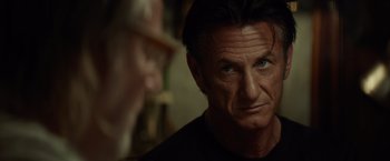 Movie still from “The Gunman” (2015), directed by Pierre Morel – A person looking at the camera; Close Up shot, Over the shoulder angle