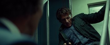 Movie still from “The Gunman” (2015), directed by Pierre Morel – A man holding a knife in his hand while standing in front of a mirror; Medium shot, Low angle