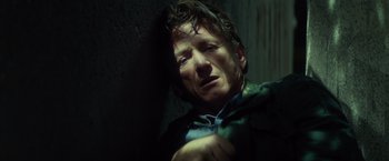 Movie still from “The Gunman” (2015), directed by Pierre Morel – A man in a dark room with his head turned to the side; Close Up shot, Low angle