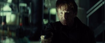 Movie still from “The Gunman” (2015), directed by Pierre Morel – A man holding a gun in a dimly - lit room; Close Up shot, Low angle