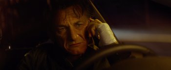Movie still from “The Gunman” (2015), directed by Pierre Morel – A man sitting in the driver's seat of a car; Close Up shot, Low angle