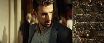 Movie still from “The Gunman” (2015), directed by Pierre Morel – A person wearing a suit; Close Up shot, Over the shoulder angle