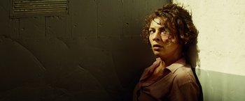 Movie still from “The Gunman” (2015), directed by Pierre Morel – A woman with curly hair standing in front of a wall; Close Up shot, Low angle