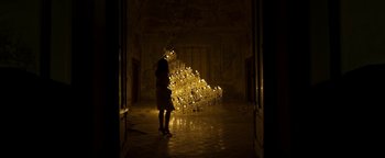 Movie still from “The Hand of God” (2021), directed by Paolo Sorrentino – A woman standing in front of a sculpture made out of candles; Extreme Wide shot, Low angle