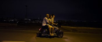 Movie still from “The Hand of God” (2021), directed by Paolo Sorrentino – Three people riding a scooter at night on the road; Wide shot, High angle
