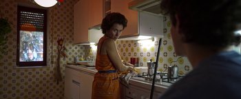 Movie still from “The Hand of God” (2021), directed by Paolo Sorrentino – A woman in an orange and white dress is washing dishes; Medium shot, Low angle