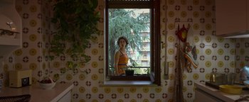 Movie still from “The Hand of God” (2021), directed by Paolo Sorrentino – A woman looking out of a window at a potted plant; Medium shot, Low angle