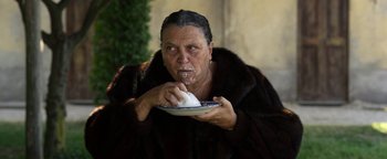 Movie still from “The Hand of God” (2021), directed by Paolo Sorrentino – An older woman eating a piece of cake on top of a plate; Medium shot, Over the shoulder angle