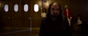 Movie still from “The Hand of God” (2021), directed by Paolo Sorrentino – A man with long hair and a goatee stares into the camera; Medium shot, Low angle