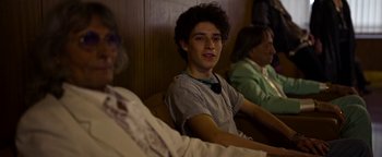 Movie still from “The Hand of God” (2021), directed by Paolo Sorrentino – A young man sitting in a chair next to a woman; Medium shot, Over the shoulder angle