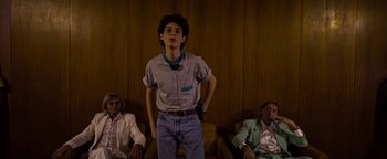 Movie still from “The Hand of God” (2021), directed by Paolo Sorrentino – A young man standing in front of two other men; Medium shot, Low angle