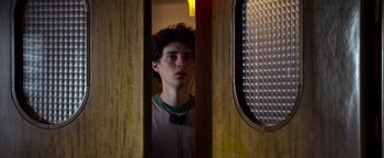 Movie still from “The Hand of God” (2021), directed by Paolo Sorrentino – A young man standing in front of an open door; Close Up shot, Low angle