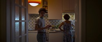 Movie still from “The Hand of God” (2021), directed by Paolo Sorrentino – A man and a woman preparing food in a kitchen; Medium shot, Low angle