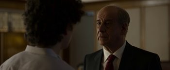 Movie still from “The Hand of God” (2021), directed by Paolo Sorrentino – An older man wearing a suit and a red neck tie; Close Up shot, Over the shoulder angle