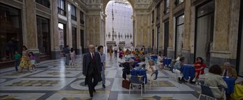Movie still from “The Hand of God” (2021), directed by Paolo Sorrentino – A group of people walking in an indoor area; Wide shot, High angle