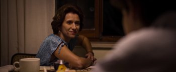 Movie still from “The Hand of God” (2021), directed by Paolo Sorrentino – A woman sitting at a table with a drink in front of her; Close Up shot, Over the shoulder angle