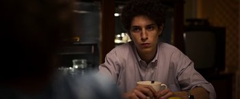 Movie still from “The Hand of God” (2021), directed by Paolo Sorrentino – A man sitting at a table with a cup of coffee; Close Up shot, Over the shoulder angle