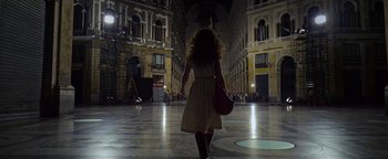 Movie still from “The Hand of God” (2021), directed by Paolo Sorrentino – A woman walking down a street holding a purse; Wide shot, Low angle