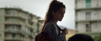 Movie still from “The Hand of God” (2021), directed by Paolo Sorrentino – A young woman with long brown hair is holding a brown bag; Close Up shot, Over the shoulder angle