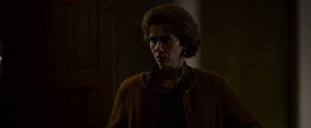 Movie still from “The Hand of God” (2021), directed by Paolo Sorrentino – An older woman wearing a brown sweater looking at the camera; Medium shot, Over the shoulder angle