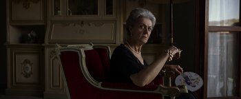 Movie still from “The Hand of God” (2021), directed by Paolo Sorrentino – An older woman sitting on a red chair; Close Up shot, Low angle