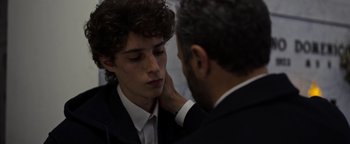 Movie still from “The Hand of God” (2021), directed by Paolo Sorrentino – A man in a suit is touching a young boy's face; Close Up shot, Over the shoulder angle