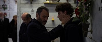 Movie still from “The Hand of God” (2021), directed by Paolo Sorrentino – A man touching another man's neck while standing next to a wall; Close Up shot, Low angle