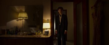 Movie still from “The Hand of God” (2021), directed by Paolo Sorrentino – A man standing in a dark room in front of a mirror; Medium shot, Low angle