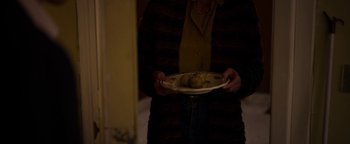 Movie still from “The Hand of God” (2021), directed by Paolo Sorrentino – A person holding a plate of food in their hands; Medium shot, High angle