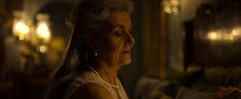 Movie still from “The Hand of God” (2021), directed by Paolo Sorrentino – An older woman wearing a white dress and pearl necklace; Close Up shot, Over the shoulder angle