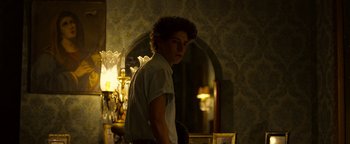 Movie still from “The Hand of God” (2021), directed by Paolo Sorrentino – A man standing in front of a mirror in a room; Medium shot, Low angle